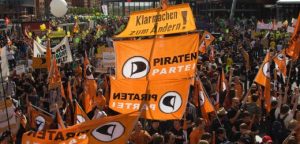 Supporters of German addition of Pirate Party (Piraten Partei) beachcomber their flags during assemblage adjoin accompaniment and accumulated surveillance behavior in Berlin
